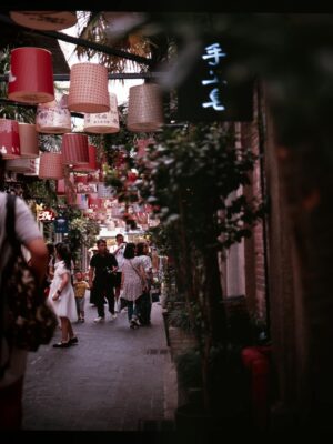 Colorful lanterns decorate a lively street in Tianzifang, Shanghai, vibrant with people.